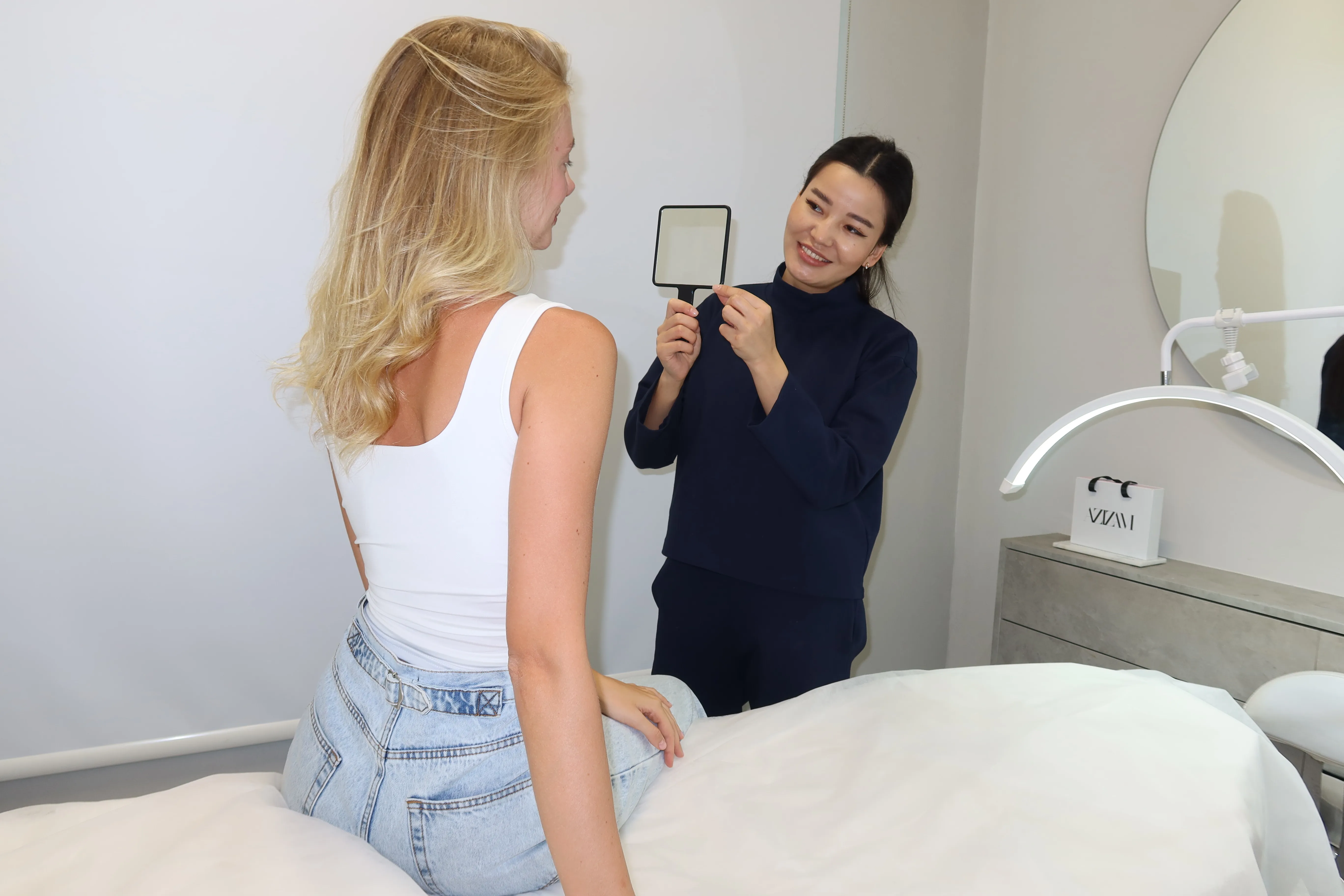 Azizam beauty salon client seeing her lash and brow result in a hand mirror, Dubai